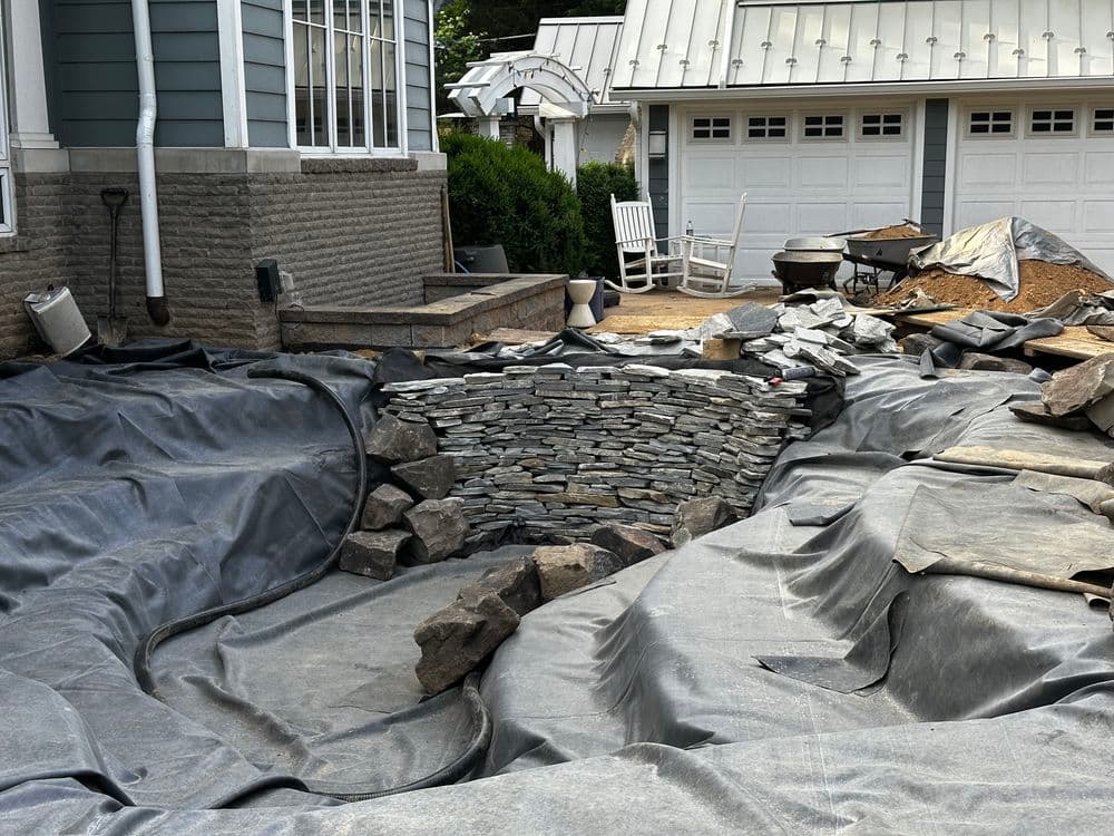Construction site with stone landscaping and black geomembrane fabric around a home.