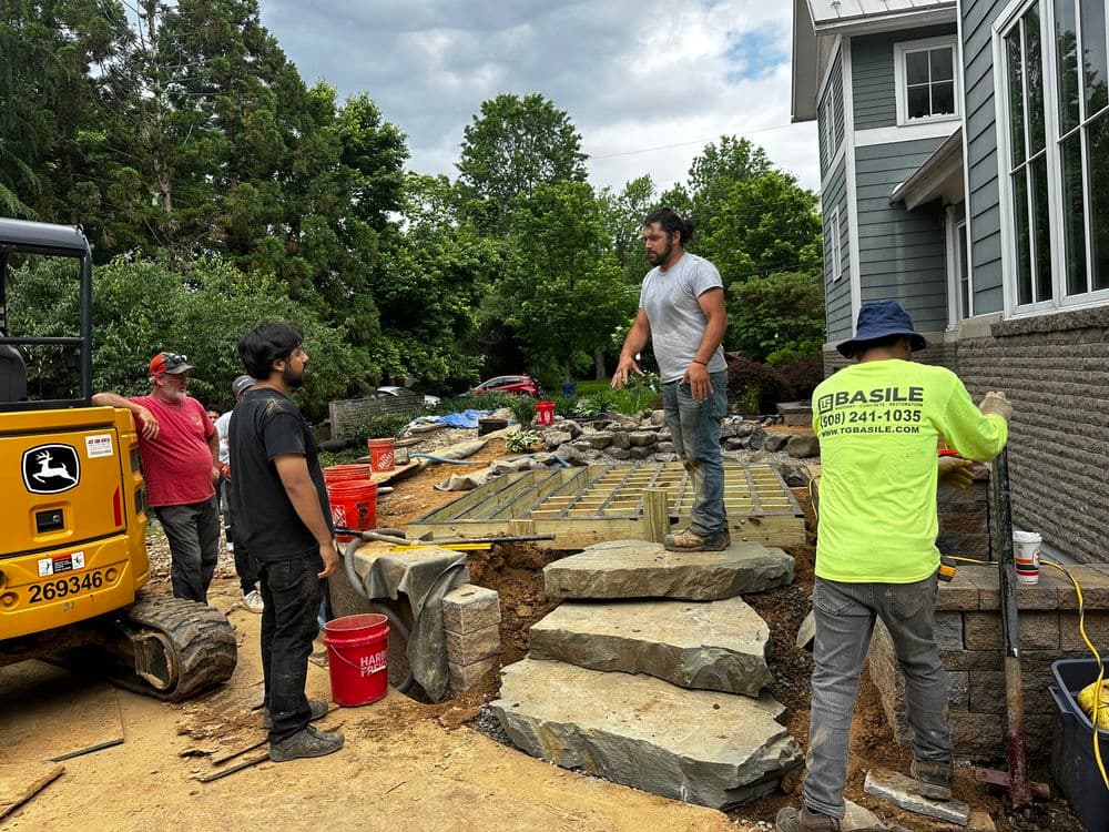 Construction workers installing stone steps in a residential landscaping project.